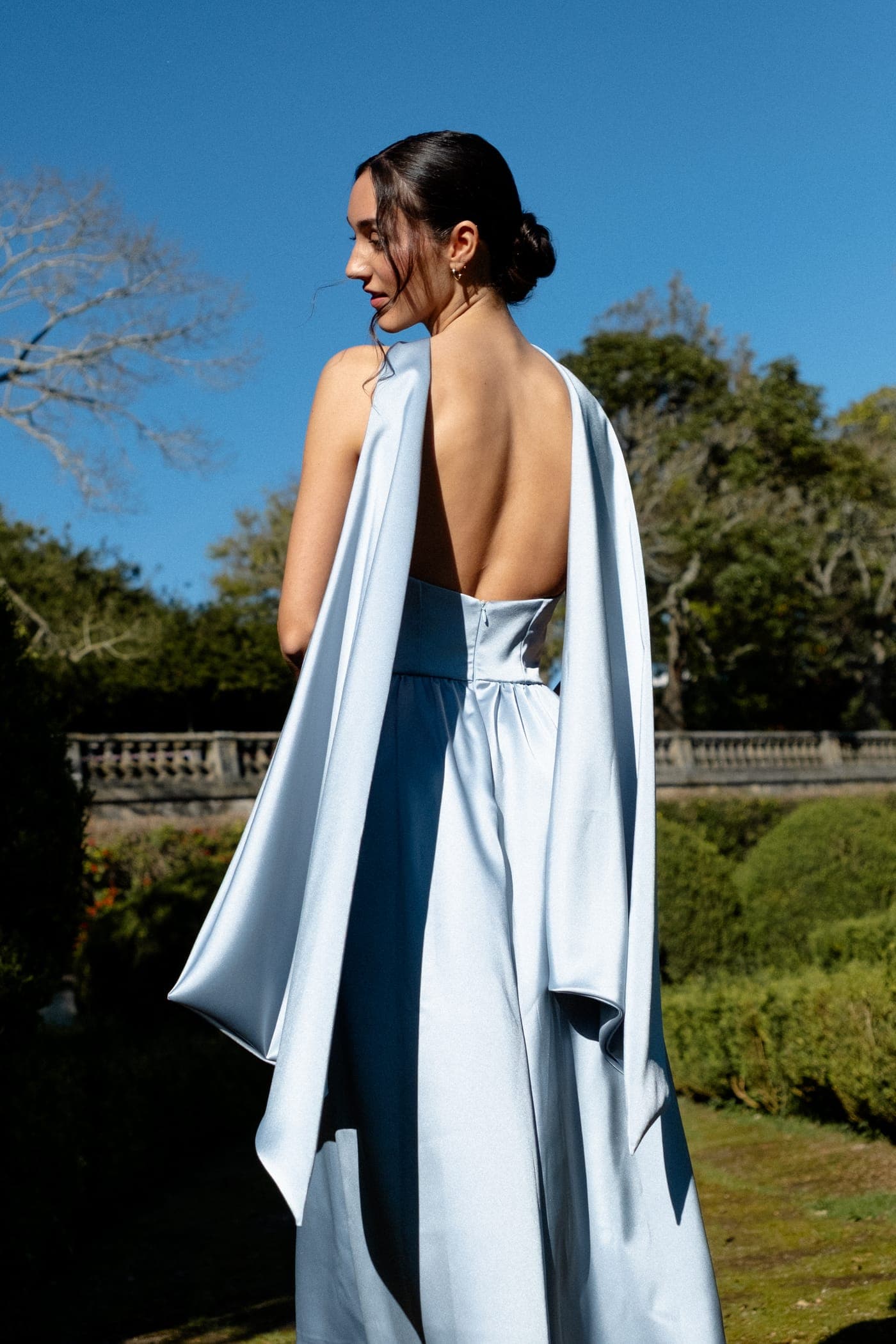 Vestido de cetim azul de costas abertas no jardim